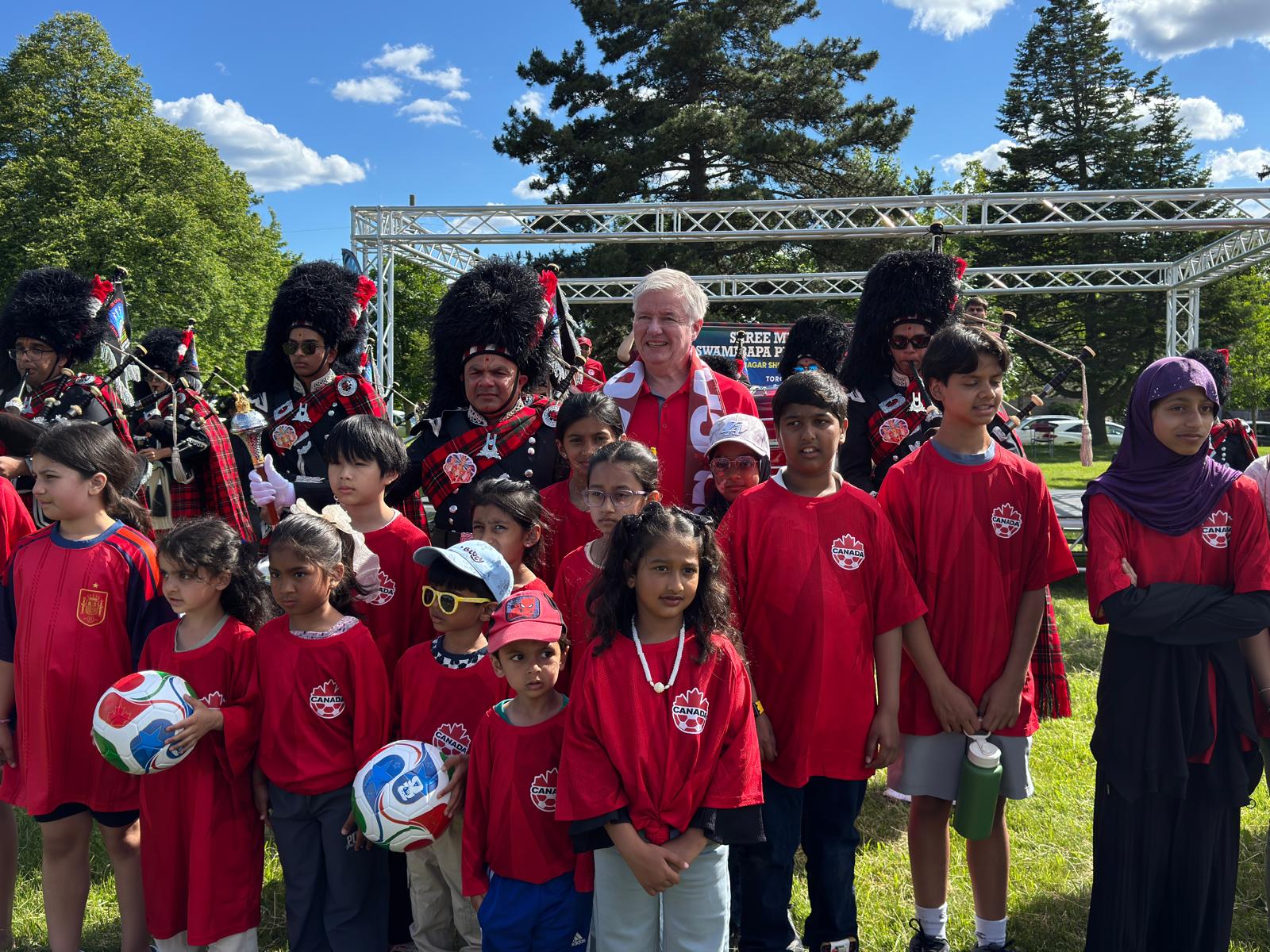 Children posing with community guests and bagpipe performers